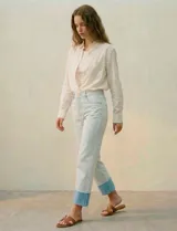 Jean de algodón de tiro medio, color celeste muy claro, con un dobladillo ancho y contrastante en color azul claro en los tobillos. El corte es recto o ligeramente holgado.