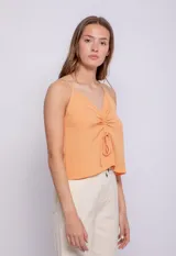 Top blanco de tirantes finos, escote en V con fruncido central ajustable mediante lazos.