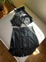 Minifalda negra de cuero sintético con flecos en el ruedo.
