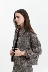 Campera de jean de mezclilla oscura, corte relajado, con cuello y bolsillos de parche con tapa y botón en el pecho. Presenta costuras en tono naranja/marrón claro.