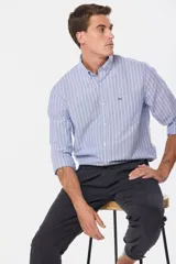 Pantalón de vestir azul a rayas verticales blancas, de corte recto, con bolsillos laterales y traseros. Se ajusta a la cintura con cinturón de cuero marrón.