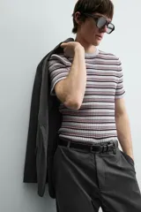 Camiseta de punto canalé slim fit, con cuello redondo y manga corta. Presenta un estampado de rayas horizontales en blanco, negro y rosado.