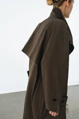 Trench oversize de Zara Woman Collection, confeccionado en mezcla de algodón con estampado de cuadros pequeños. Presenta cuello alto, cierre frontal con botones, mangas largas con trabillas ajustables y bolsillos laterales.