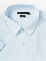 Camisa de manga corta blanca de algodón con efecto lino, cuello camisero, cierre frontal con botones y bolsillo ojal en el pecho.