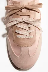 Championes de diseño ligero y femenino en color rosado, con exterior de tela satinada y detalles en gamuza sintética en la puntera y el talón. Cuentan con cordones planos al tono y una suela plana de goma color marrón con textura acanalada.