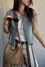 Chaleco de denim celeste sin mangas, con detalles de costuras decorativas en zig-zag y aplicaciones en tono suela en los bordes y bolsillos.