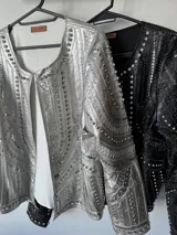 Chaqueta negra de cuero sintético con tachas plateadas, lentejuelas y strass.