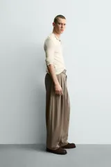 Pantalón de corte balloon fit en color gris, confeccionado en tejido con viscosa. Presenta pliegues frontales, cintura con cinturón integrado a contraste, bolsillos laterales y bolsillos traseros de vivo.