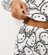 Pijama de dos piezas con estampado integral de Hello Kitty. Incluye una blusa de manga larga con cuello redondo y un pantalón con cintura elástica, confeccionado en tejido acanalado.