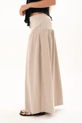 Pollera larga de corte evasé en color arena, con detalle de costura horizontal y frunces en la parte inferior que le otorgan volumen y movimiento.