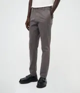 Pantalón slim de sarga lavada color marrón, con cierre de botón y cremallera, trabillas para cinturón y bolsillos laterales y traseros.