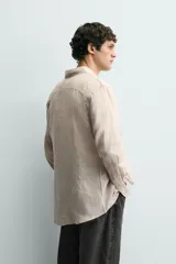 Camisa celeste de lino de corte regular fit, con cuello abotonado, manga larga y cierre frontal de botonadura.