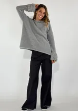 Sweater gris de manga larga con cuello redondo y puños con detalle de volados de lana rizada.