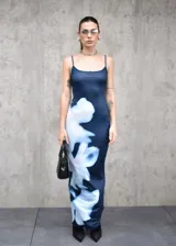 Vestido largo de corte ajustado, confeccionado en tela elastizada de color azul oscuro con un estampado floral abstracto en tonos blancos que recorre el lateral de la prenda. Presenta escote redondo y breteles finos.