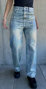 Pantalón de jean celeste con estampado de cuadrados plateados reflectantes.