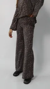 Conjunto de dos piezas compuesto por un sweater de cuello redondo y mangas largas holgadas, y un pantalón de corte recto, ambos confeccionados en tejido acanalado con estampado animal print de leopardo en tonos marrones y grises.