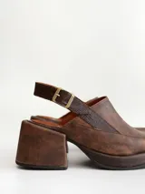 Zapato tipo zueco de cuero color chocolate con efecto desgastado, plataforma y taco cuadrado. Presenta una tira trasera ajustable con hebilla metálica.