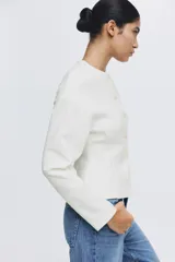 Blazer de botonadura sencilla en tejido efecto neopreno color blanco. Modelo de hombros caídos con escote redondo, botones hasta la cintura y corte acampanado de cintura a bajo.