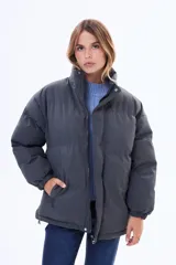 Campera puffer de corte holgado, color negro, con cuello alto, cierre frontal y puños elásticos.