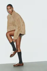 Chaqueta de ante color tostado con cuello solapa, manga larga con puño, bolsillos con solapa en el delantero y cierre frontal con botones.