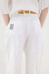 Pantalón de lino marrón de tiro medio, con calce holgado y diseño de piernas amplias. Cuenta con bolsillos traseros, trabillas para cinto y un pin bordado en contraste.
