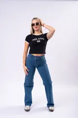 Remera negra de corte ajustado con cuello y bordes de mangas en color crema. Presenta un estampado frontal con la palabra 'MILANO' y el número '96' rodeado por una corona de laureles.