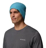 Gorro tipo beanie de tejido acanalado en color azul brillante, con etiqueta de la marca Columbia en el borde lateral.