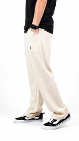 Pantalón de punto color beige, de corte recto y holgado, con cintura elástica y pequeño logo bordado en la parte superior.