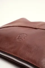 Cartera bandolera de cuero marrón con forma relajada, diseño de costuras curvas y detalles de nudos hechos a mano en las asas.