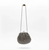 Bolso de mano tejido artesanalmente en hilo gris con detalles de canutillos en tono peltre. Presenta una boquilla metálica estilo vintage con cierre a presión y una cadena larga plateada para llevar al hombro.