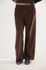 Pantalón de pana de algodón con corte de pierna ancha y tiro medio-bajo. Presenta un diseño con bolsillos delanteros y traseros, y un aplique cuadrado distintivo en una de las piernas.