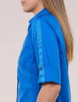 Camisa roja de poplín de algodón, de silueta semi entallada con cuello camisero y escote en V. Cuenta con cierre frontal de botones metálicos, bolsillos plaqué en el pecho y mangas 3/4 arremangables con presilla y argolla metálica.
