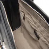 Cartera tipo tote de cuero sintético negro con textura granulada. Presenta doble asa superior, correa ajustable extraíble y detalle de tira decorativa con cierre metálico frontal. Incluye logo metálico de la marca en la parte inferior.