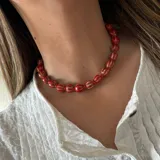 Collar corto de cuentas rojas con líneas horizontales blancas y cadena plateada para regular el largo.