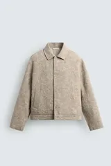 Cazadora de corte regular confeccionada en tejido de algodón con textura jacquard floral. Presenta cuello solapa, manga larga, cierre frontal con botones y bolsillos laterales de vivo.