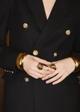 Chaqueta tipo blazer de doble botonadura en color negro, con solapas de muesca, bolsillos frontales con solapa y cierre de botones dorados. Presenta un diseño estructurado con forro interior.