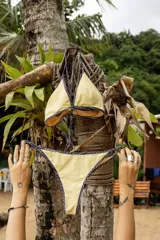 Conjunto de bikini compuesto por un corpiño triangular y una bombacha de corte clásico. El diseño presenta una combinación de colores en bordó, con detalles de ribetes en rosa y mostaza en los bordes y tirantes.