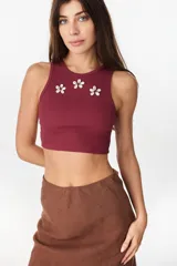 Musculosa de algodón en color bordó, de corte corto, con cuello redondo y detalles de flores decorativas aplicadas en el pecho.
