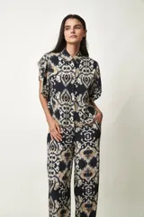 Camisa Girasol de manga corta color negro, con cuello camisero, cierre frontal de botones y mangas con volados drapeados.