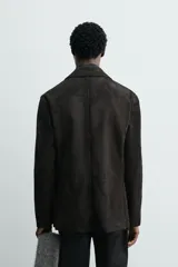 Blazer de corte regular confeccionado en piel con acabado de ante. Presenta cuello con solapas de muesca, cierre frontal de dos botones, bolsillos con solapa en la cadera y aberturas en la espalda.