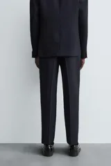 Pantalón de corte recto confeccionado en tejido con lana, color beige. Presenta bolsillos frontales, bolsillos traseros de vivo y cierre frontal con cremallera y botón.