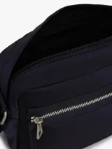 Morral cruzado Tommy Hilfiger de diseño práctico y funcional, confeccionado en poliamida reciclada azul marino con forro de poliéster. Cuenta con un compartimento principal, bolsillo exterior con cierre de cremallera, correa ajustable extraíble y detalles distintivos con la bandera metalizada de la marca.