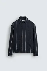 Sobrecamisa de hombre, corte relajado, color azul marino con rayas verticales blancas. Presenta cuello solapa, manga larga con puños abotonados, bolsillos de parche delanteros y cierre frontal de botones.