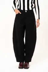 Pantalón de tiro medio con silueta curvada, más ancha en la zona de los muslos y rodillas, con cierre frontal de cremallera y botón.