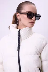 Campera puffer de corte oversize y largo medio, color blanco, con cuello alto, cierre frontal y aberturas laterales con botones a presión.