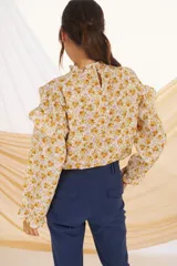 Blusa de manga larga con estampado floral en tonos mostaza y lila, con cuello y puños con volados.