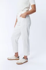 Pantalón jean de corte carrot color crudo, tiro alto, con bolsillos laterales y traseros, y cierre frontal con botón y cremallera.