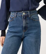 Pantalón wide leg de tiro alto confeccionado en jean de algodón, con pretina con pasacintos, cierre frontal con botón y cremallera, y bolsillos delanteros y traseros.