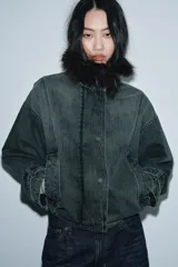 Chaqueta tipo bomber de denim lavado azul, corte holgado, con cuello solapa y aplicación de pelo sintético marrón desmontable. Presenta bolsillos delanteros y bajo acabado en elástico.