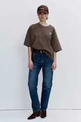 Remera blanca de corte oversize con cuello redondo y mangas cortas, presenta un pequeño bordado de cerezas en el pecho.